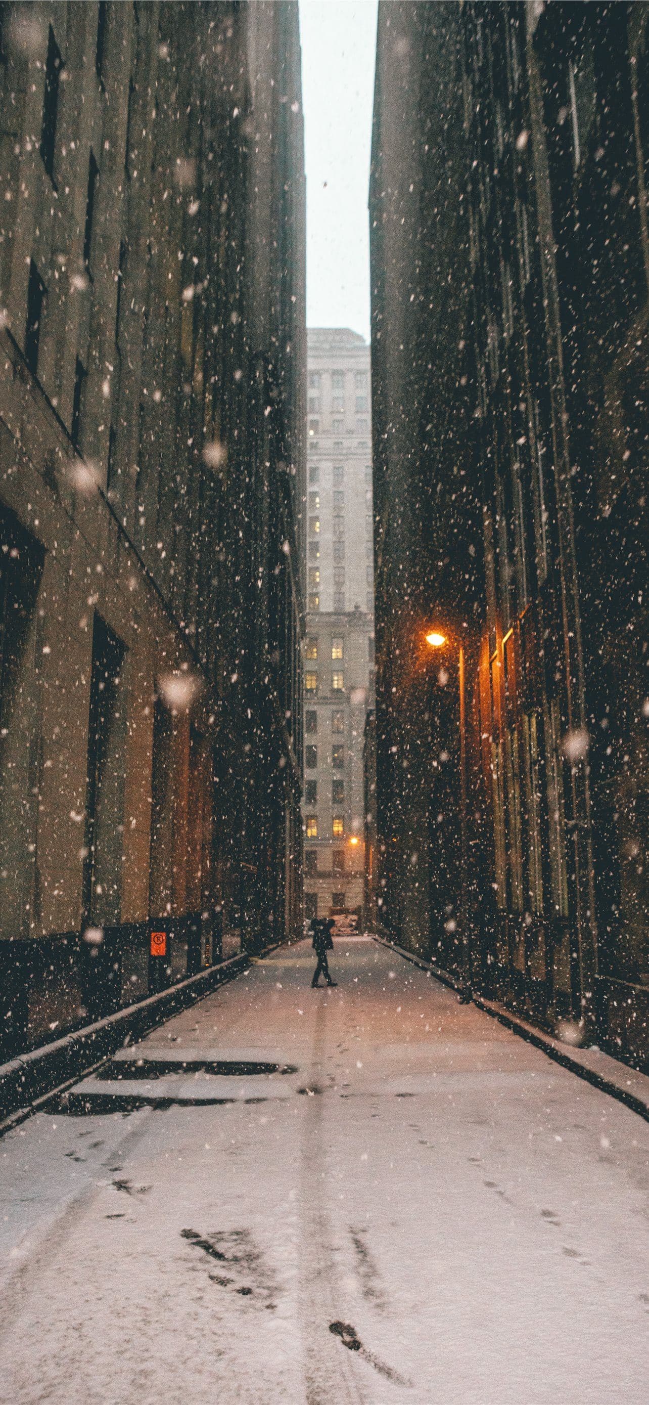 Person Standing Between Brown High Rise Buildings